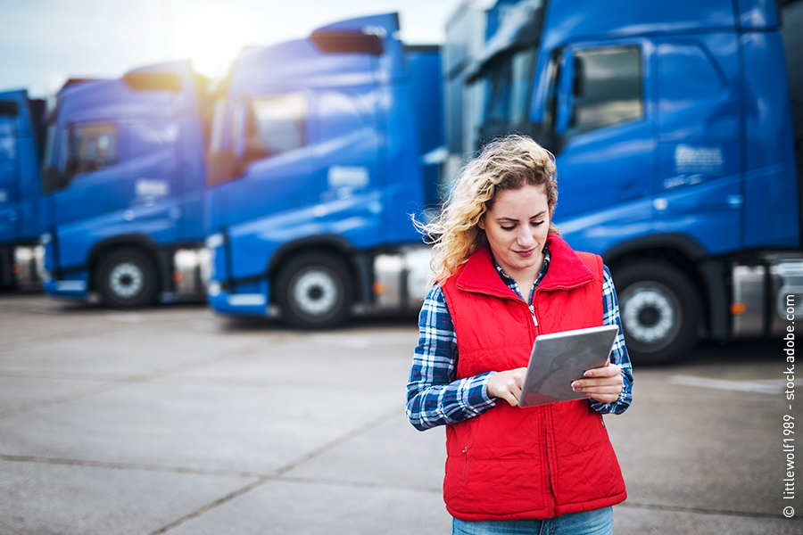LKW-Fahrerin mit Tablet vor Fuhrpark
