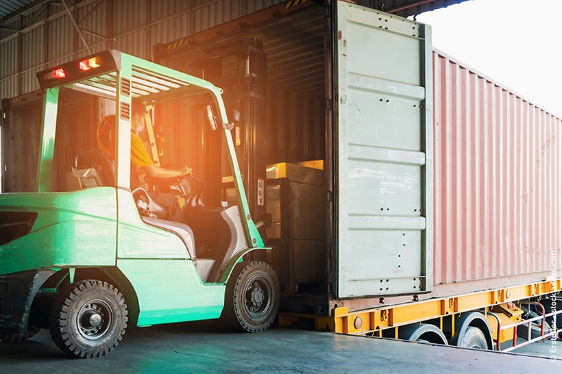 ein-lkw-mit-offener-heckklappe-steht-an-einer-laderampe-und-wird-von-einem-gabelstapler-beladen-