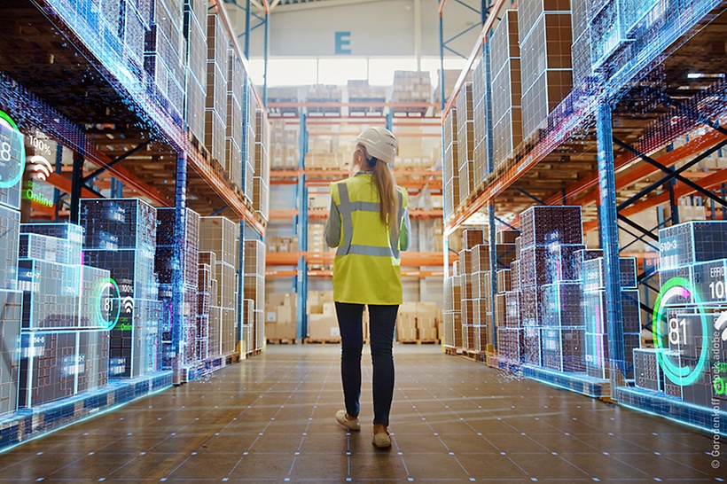 eine-frau-mit-warnweste-läuft-durch-ein-digitalisiertes-lager